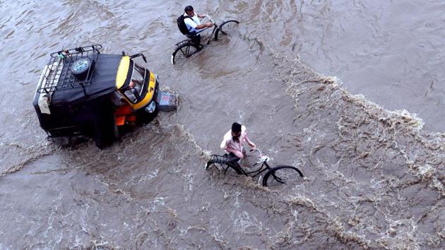Cyclists wade next to an auto rickshaw along a flooded street after heavy rains in Patiala. (AFP) Cyclists wade next to an auto rickshaw along a flooded street after heavy rains in Patiala. (AFP)