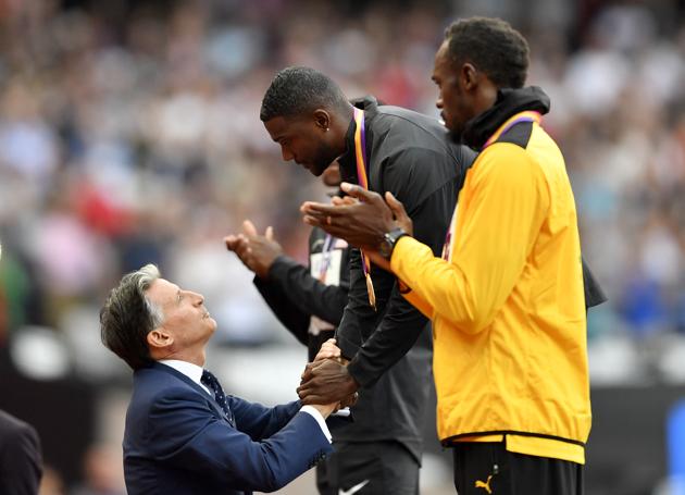 Gold medallist Justin Gatlin receives his prize from IAAF president Sebastian Coe as Usain Bolt cheers on during the podium ceremony of the men’s 100m event at the IAAF World Championships of Athletics in London on Sunday (AP)