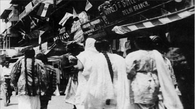 Women pass by one of the bazars of Delhi, with its storefronts decorated with the Indian national flag on August 15, 1947. (PIB) 