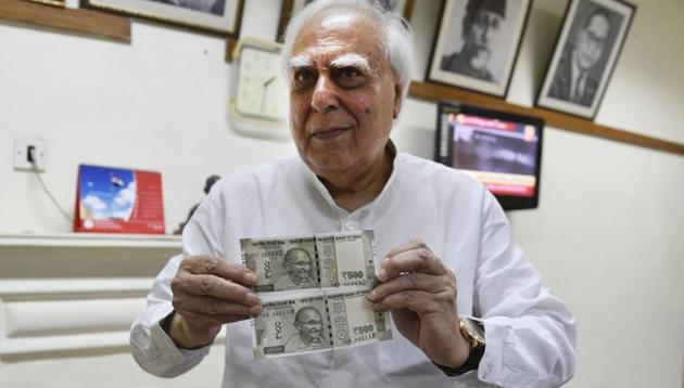 Congress leader Kapil Sibal shows the two kinds of Rs 500 notes in New Delhi on Tuesday.(Mohd Zakir/HT PHOTO)