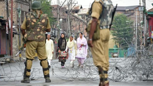 Paramilitary troopers stand guard as Kashmiri pedestrians walk along a road during restrictions n August 2, 2017. (AFP) Paramilitary troopers stand guard as Kashmiri pedestrians walk along a road during restrictions n August 2, 2017. (AFP)