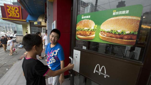 File photo of two boys opening the door to a McDonald's restaurant in Beijing, China. On August 8, 2017, McDonald's said it plans to nearly double the number of restaurants in China in the next five years, eventually surpassing Japan as the chain’s second-biggest market outside the United States.(AP)