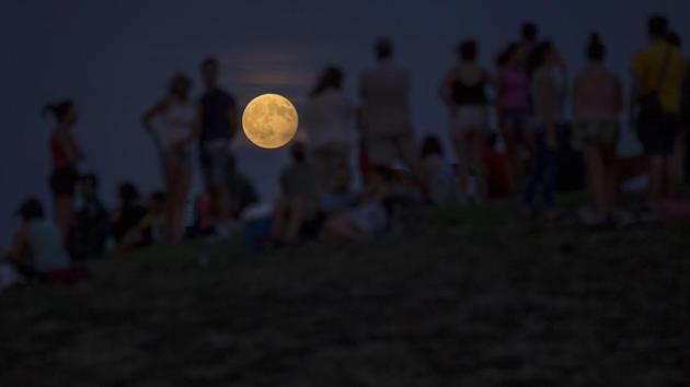 People watch a rising full moon during a partial lunar eclipse atop a hill at the Tio Pio park in Madrid. A lunar eclipse or solar eclipse is not visible every month as the moon’s orbit is tilted about 5 degrees off from Earth’s orbit. (Francisco Seco/AP)