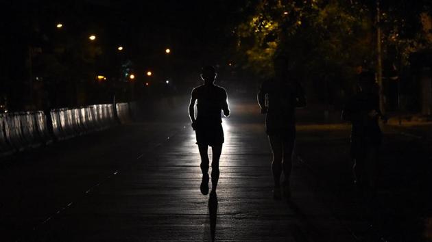 Samir Singh (C) is silhouetted by car’s headlights during an early morning sprint in Mumbai. Dressed in a blue sports vest, Singh started each day in the early hours from the northern Mumbai slums and headed to the business district in the city’s south. (Indranil Mukherjee / AFP)