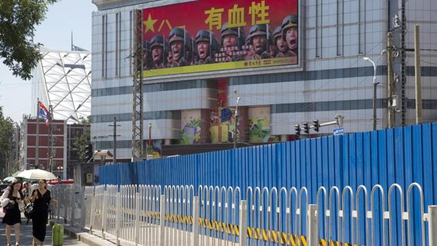 People walk near a billboard advertising the Chinese military with words that mean "Courageous", in Beijing, China. China is intensifying its warnings to Indian troops. (AP File Photo) People walk near a billboard advertising the Chinese military with words that mean "Courageous", in Beijing, China. China is intensifying its warnings to Indian troops. (AP File Photo)