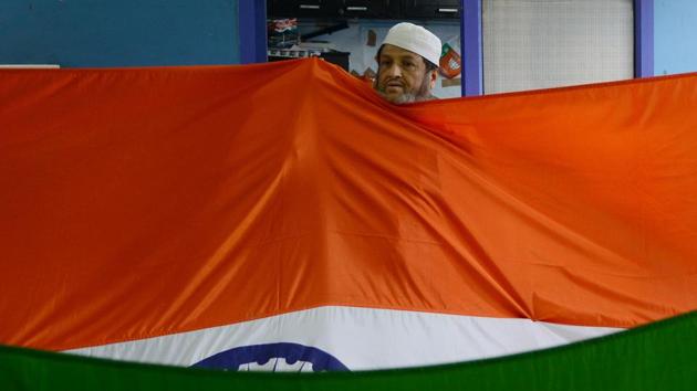 A man folds the tricolour for sale ahead of the upcoming Independence day celebrations at a workshop in New Delhi. (Money Sharma/AFP)