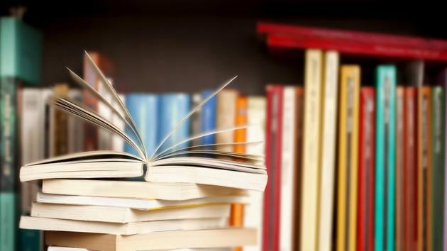 Stack of books on a wooden library shelf, one of them open on top, multicolored book spines background. (Getty Images/iStockphoto) Stack of books on a wooden library shelf, one of them open on top, multicolored book spines background. (Getty Images/iStockphoto)