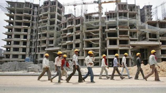 Workers walk in front of the construction site of a commercial complex on the outskirts of Ahmedabad.(REUTERS)