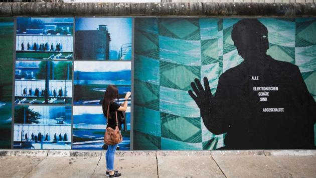 A woman takes pictures of the installation "Beyond The Wall" by German artist Stefan Roloff that is mounted on remnants of the former Berlin Wall.(AFP Photo)