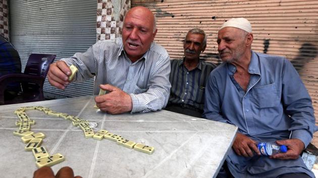 Iraqi men play dominos at a cafe in the old city in west Mosul, one among growing sights of people foregoing the torment of past years and picking their lives back up. (SAFIN HAMED / AFP)