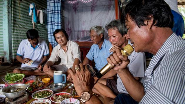 Tang Van Cuol (R) sings into a microphone interpreting a karaoke tune from his mobile phone during a celebratory meal with other shrimp farmers. Wealth from shrimp farming has transformed Cuol’s part of Soc Trang province, with motorcycles replacing bicycles, on paved roads dotted with multi-storey concrete homes - sights unimaginable a generation prior. (Roberto Schmidt / AFP) Tang Van Cuol (R) sings into a microphone interpreting a karaoke tune from his mobile phone during a celebratory meal with other shrimp farmers. Wealth from shrimp farming has transformed Cuol’s part of Soc Trang province, with motorcycles replacing bicycles, on paved roads dotted with multi-storey concrete homes - sights unimaginable a generation prior. (Roberto Schmidt / AFP)