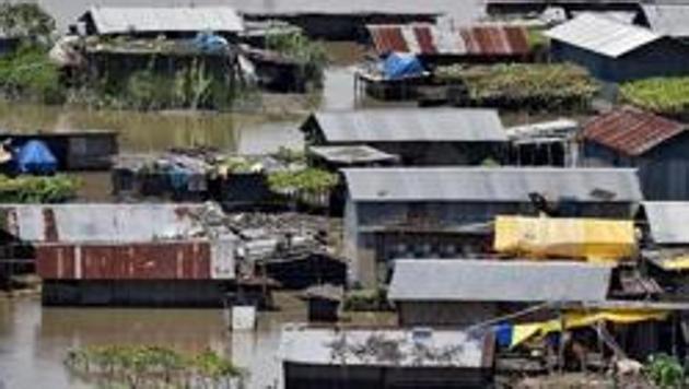 Villagers use a boat as they row past partially submerged houses at a flood-affected village in Morigaon district in Assam on July 14. (Reuters)