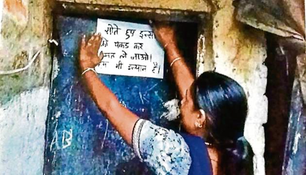 A Pardhi woman pasting a poster asking police not to pick up people from their homes while they are sleeping.ht photo