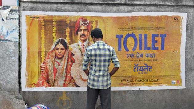 An Indian man urinates on a wall on the roadside in front of a poster for the Hindi film ‘Toilet’ in Hyderabad on August 12, 2017. (Noah Seelam/AFP)