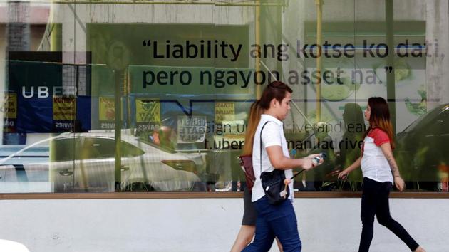 People walk past an Uber advertisement outside the Uber main office in Mandaluyong city, metro Manila, Philippines, on August 15, 2017. A streamer reads "My car was a liability before but now it's an asset". (Reuters) People walk past an Uber advertisement outside the Uber main office in Mandaluyong city, metro Manila, Philippines, on August 15, 2017. A streamer reads "My car was a liability before but now it's an asset". (Reuters)