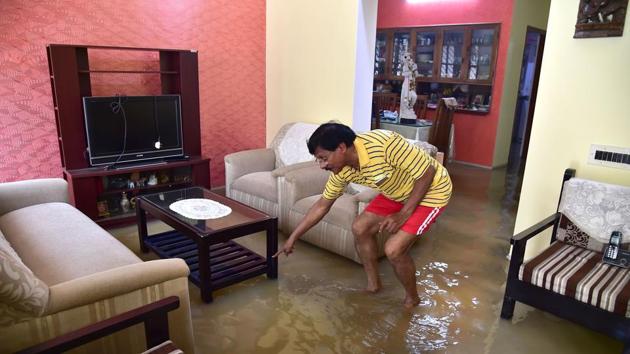 An Indian resident looks for a lost item in his flooded house situated in a low lying area in Bengaluru on August 15, 2017.(AFP)