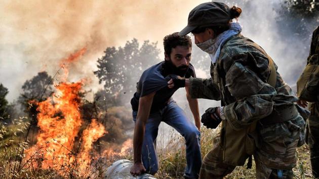 Firemen, army personnel and volunteers work to extinguish a fire east of the Greek capital Athens on August 15, 2017. The army was called in to assist firefighters around Kalamos, setting up bulldozers as firebreaks around the area. (Aris Messinis / AFP)
