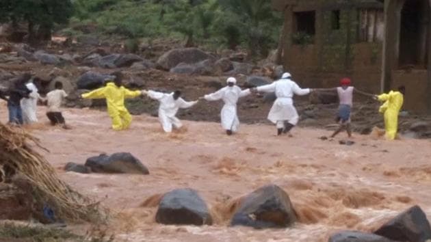 People wearing protective suits hold hands as they cross a river after the mudslide in the mountain town of Regent, Sierra Leone. The Red Cross estimates that another 600 people are still missing or buried in the rubble. The President of the West African nation Ernest Bai Koroma said the country is in a state of grief and mourning. (REUTERS TV)