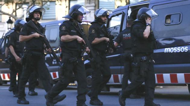 Spanish police officers brandishing hand guns and automatic weapons launched a manhunt in the downtown district ordering stores, cafes and public transport to shut down. (Pau Barrena/AFP)