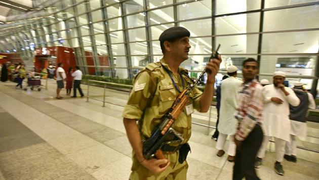 A securityman at the Delhi airport talks on walkie-talkie even as passengers look on. The airport saw a brief pause in operations on Sunday after a pilot raised an alarm about a drone-like object.(Sanjeev Verma/HT File Photo)