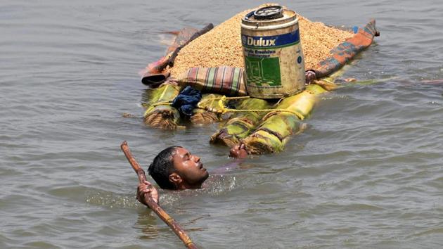 A villager carries grains on a banana raft as he shifts from a flooded village in Araria district of Bihar on Monday. (PTI)