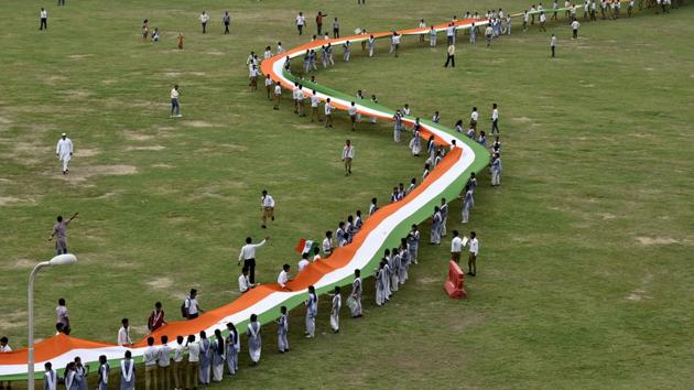 School children hold a thousand feet long National flag organized by consumer rights organization at Noida stadium, in Noida on Monday. (Virendra Singh Gosain/HT PHOTO)