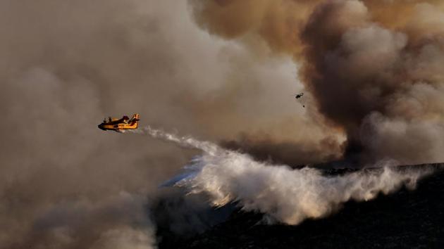 A Canadair firefighting airplane drops water above a fire at sunset, east of Athens on August 15, 2017. (Aris Messinis/AFP)