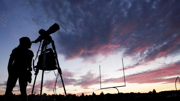 A woman looks through a telescope on the football field at Madras High School the evening before a solar eclipse in Madras, Oregon.(Reuters)