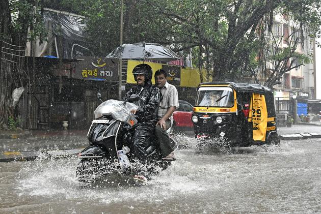 A two-wheeler drives through a flooded street in Versova on Sunday. (HT PHOTO) A two-wheeler drives through a flooded street in Versova on Sunday. (HT PHOTO)