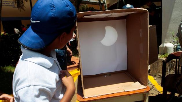 A student looks at solar eclipse on a box in Managua, Nicaragua. A number of towns within the total eclipse’s path set up viewing parties. At the Southern Illinois University campus in Carbondale, Illinois, the 15,000 seat football stadium was sold out for Monday. (Oswaldo Rivas/REUTERS)