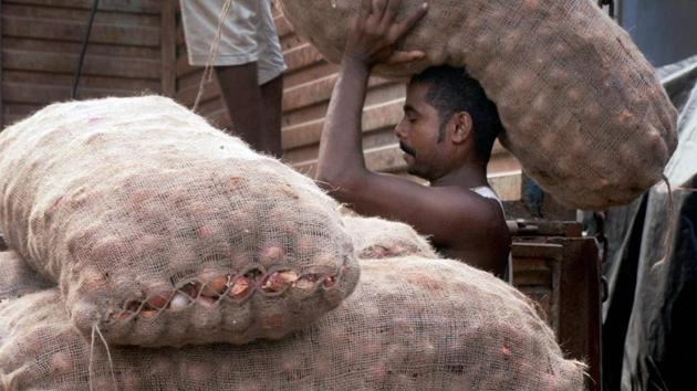 A labourer unloads onion sacks from a truck at a wholesale vegetable market in Kolkata. The price of onions has gone up due to shortage of crop. (PTI Photo) A labourer unloads onion sacks from a truck at a wholesale vegetable market in Kolkata. The price of onions has gone up due to shortage of crop. (PTI Photo)