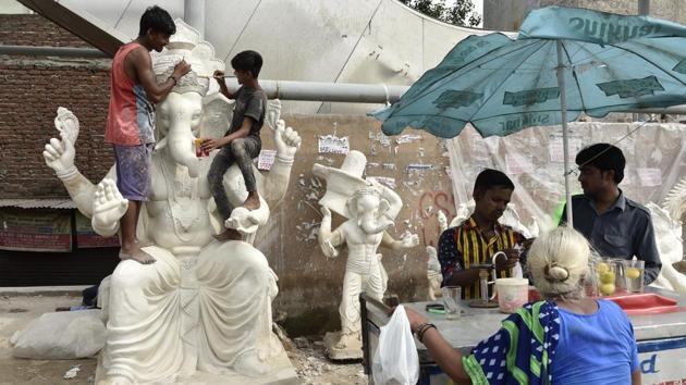 A Ganesha idol is worked on by craftsmen while out in the open to dry its plaster. The size and intricacy, as well as the materials used in its making determine the price of the idol. While Plaster of Paris was a go-to option, its negative impact has brought about increased demand for clay based pieces which are eco-friendly, but take considerably longer periods to manufacture. (Burhaan Kinu / HT Photo)
