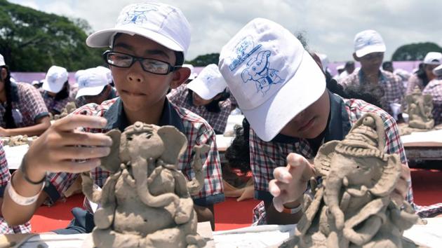 Two schoolchildren engrossed in making the idol. (Pratham Gokhale/HT PHOTO)