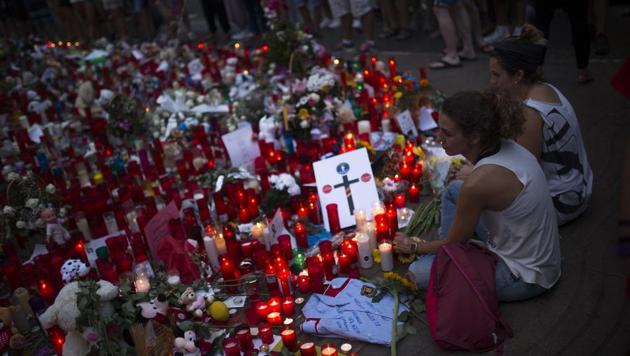 Two women holding hands sit next to candles and flowers placed on the ground for the victims of an attack that left many killed and wounded in Barcelona, Spain on August 23. (AP Photo) Two women holding hands sit next to candles and flowers placed on the ground for the victims of an attack that left many killed and wounded in Barcelona, Spain on August 23. (AP Photo)
