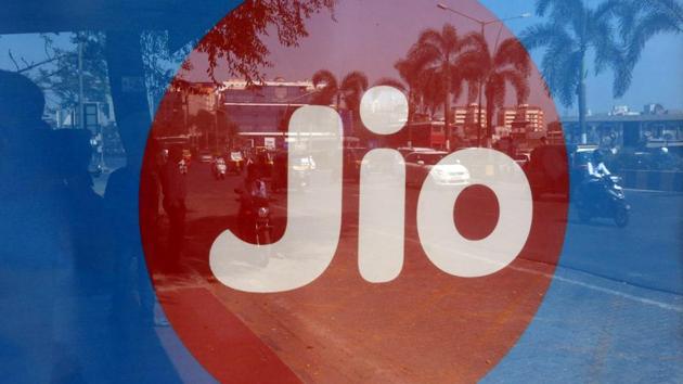 Commuters are reflected on an advertisement of Reliance Industries' Jio telecoms unit, at a bus stop in Mumbai.(REUTERS)