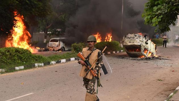 Indian security personnel walks past burning vehicles set alight by the followers of Gurmeet Ram Rahim. (AFP)