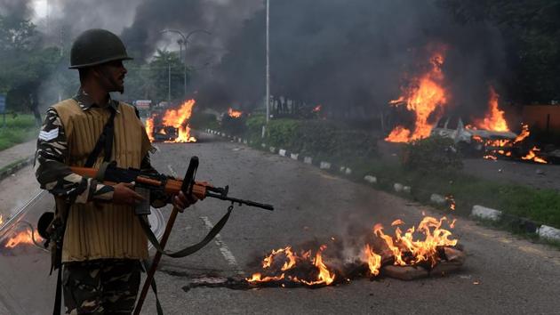 Indian security personnel looks at burning vehicles set alight by rioting followers of Gurmeet Ram Rahim. (AFP)