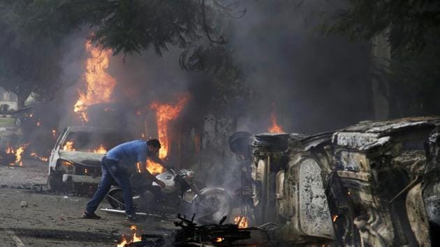 A man lifts a motorbike in a vandalized area by Dera Sacha Sauda sect members in Panchkula. Deadly riots have broken out in Panchkula. (AP)