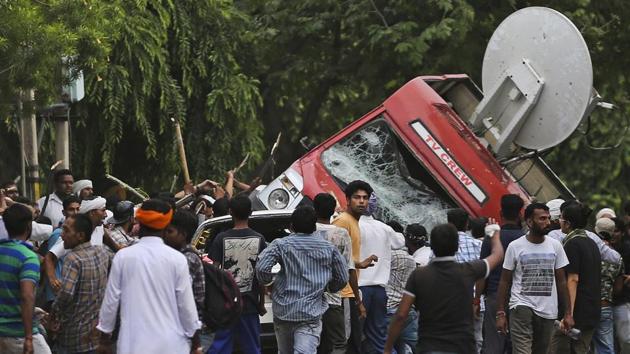 Dera Sacha Sauda sect members overturn an OB van on the streets of Panchkula, after a court convicted Gurmeet Ram Rahim of raping two of his followers. (AP)