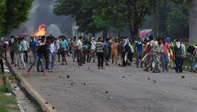 Followers of Gurmeet Ram Rahim Singh throw stones at security forces during clashes after the dera chief was convicted of rape in Panchkula. (AFP) Followers of Gurmeet Ram Rahim Singh throw stones at security forces during clashes after the dera chief was convicted of rape in Panchkula. (AFP)