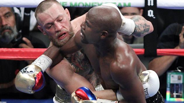 Mixed martial arts star Conor McGregor (L) competes with boxer Floyd Mayweather Jr. during their fight.(AFP)