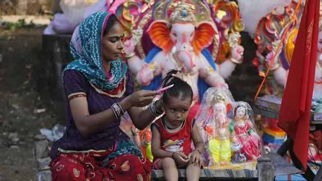 An Indian woman combs the hair of a child as she waits for customers for idols of the elephant headed Hindu god Ganesha ahead of Ganesh Chaturthi festival in Ahmedabad. (Ajit Solanki/AP) 