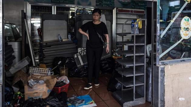 A woman stands in a convenience store as they cleanup in the aftermath of Typhoon Hato and prepare for tropical storm Pakhar with taped-up windows in Macau on August 26, 2017.(AFP)