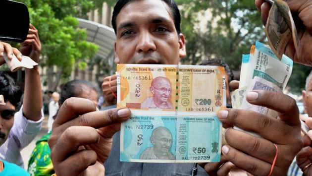 A man shows new currency notes of Rs 200 and Rs 50 outside the Reserve Bank of India in New Delhi on Friday. (PTI) 