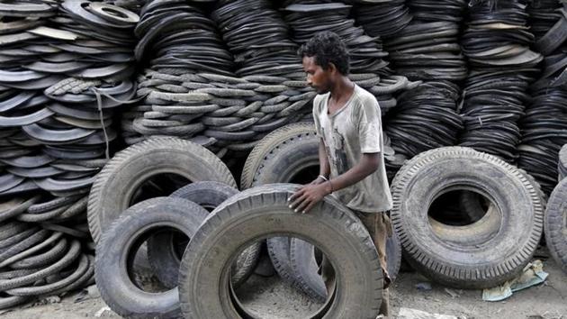 A man takes a tyre to cut at a tyre recycling unit on the outskirts of Ahmedabad. (Amit Dave/ REUTERS) 