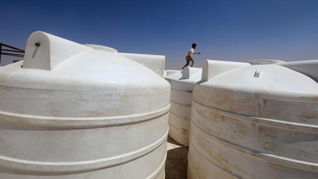 A displaced child from the Islamic State (IS) group's Syrian stronghold of Raqa, runs along to top of water containers at a camp in Ain Issa on August 22, 2017. (Delil Souleiman/ AFP) A displaced child from the Islamic State (IS) group's Syrian stronghold of Raqa, runs along to top of water containers at a camp in Ain Issa on August 22, 2017. (Delil Souleiman/ AFP)