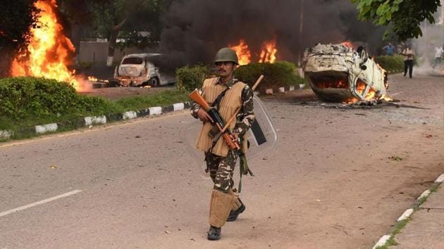 A security personnel walks past burning vehicles set alight by rioting followers of religious leader Gurmeet Ram Rahim of Dera Sacha Sauda who was convicted of rape in Panchkula on August 25. (AFP) A security personnel walks past burning vehicles set alight by rioting followers of religious leader Gurmeet Ram Rahim of Dera Sacha Sauda who was convicted of rape in Panchkula on August 25. (AFP)