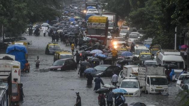 People walk trough a water logged street at Matunga in Mumbai, on Tuesday, August 29, 2017.(Kunal Patil/Hindustan Times)