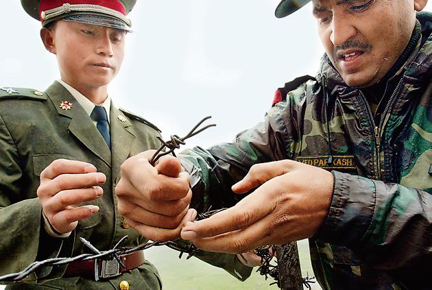 (FILES) A file photo of a Chinese soldier (L) and an Indian soldier placing a barbed wire fence following a meeting of military representatives at the Nathu La border in Sikkim, India. India said on August 28, 2017 that troops were disengaging from a months-long stand-off with the Chinese military on a strategically important area of disputed territory in the Himalayas.(AFP)