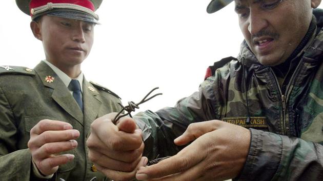File photo from July 2006 shows a Chinese soldier (left) and an Indian soldier placing a barbed wire fence following a meeting of military representatives at the Nathu La border crossing in India's northeastern Sikkim state. India said on August 28, 2017 that troops were disengaging from a months-long stand-off with the Chinese military in the strategically important Doklam area. (AFP) File photo from July 2006 shows a Chinese soldier (left) and an Indian soldier placing a barbed wire fence following a meeting of military representatives at the Nathu La border crossing in India's northeastern Sikkim state. India said on August 28, 2017 that troops were disengaging from a months-long stand-off with the Chinese military in the strategically important Doklam area. (AFP)